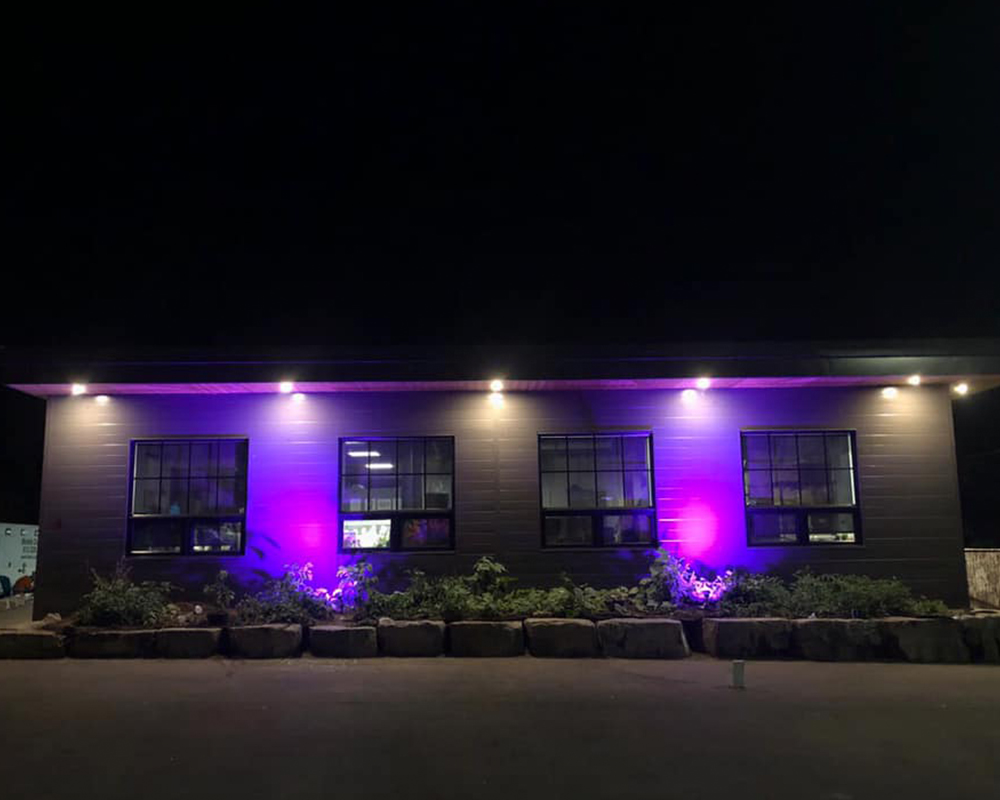 Outdoor facade of the Integrated Care Hub building lit in purple lights.