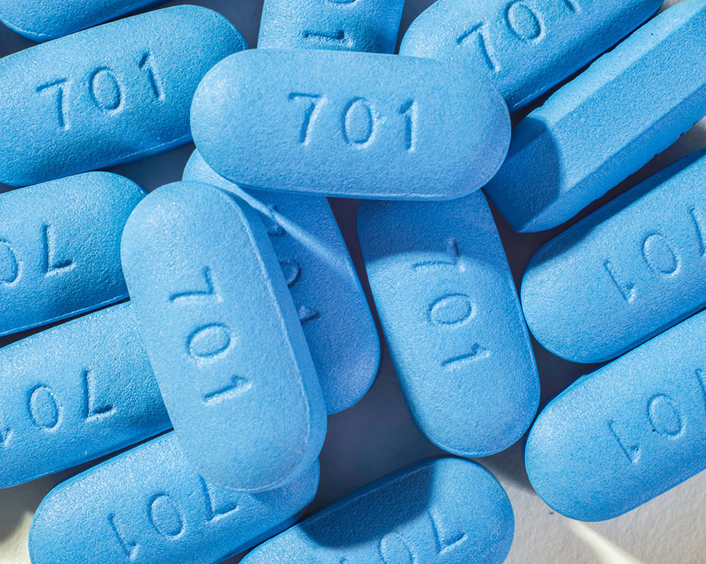 A pile of blue pills with the number 701 engraved on them are scattered across filling the image.